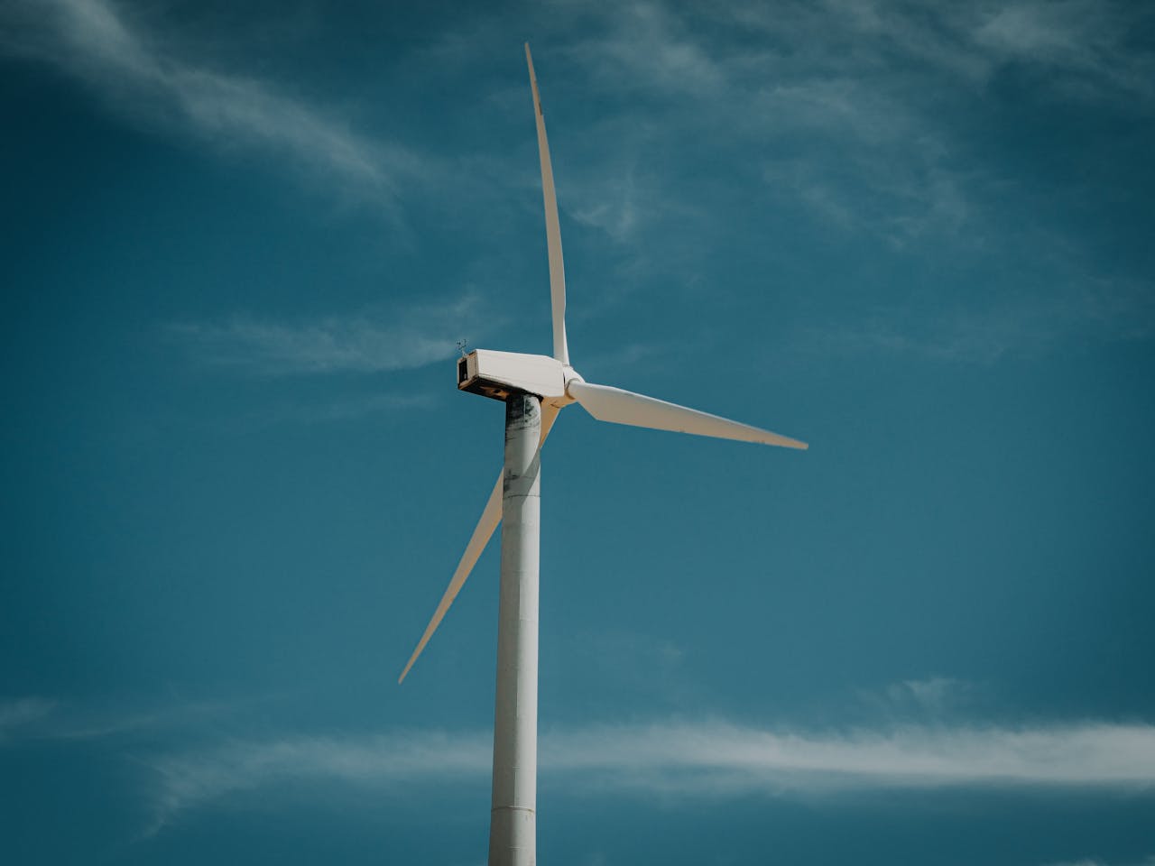 Wind turbine generating renewable energy under a clear blue sky, symbolizing sustainability.