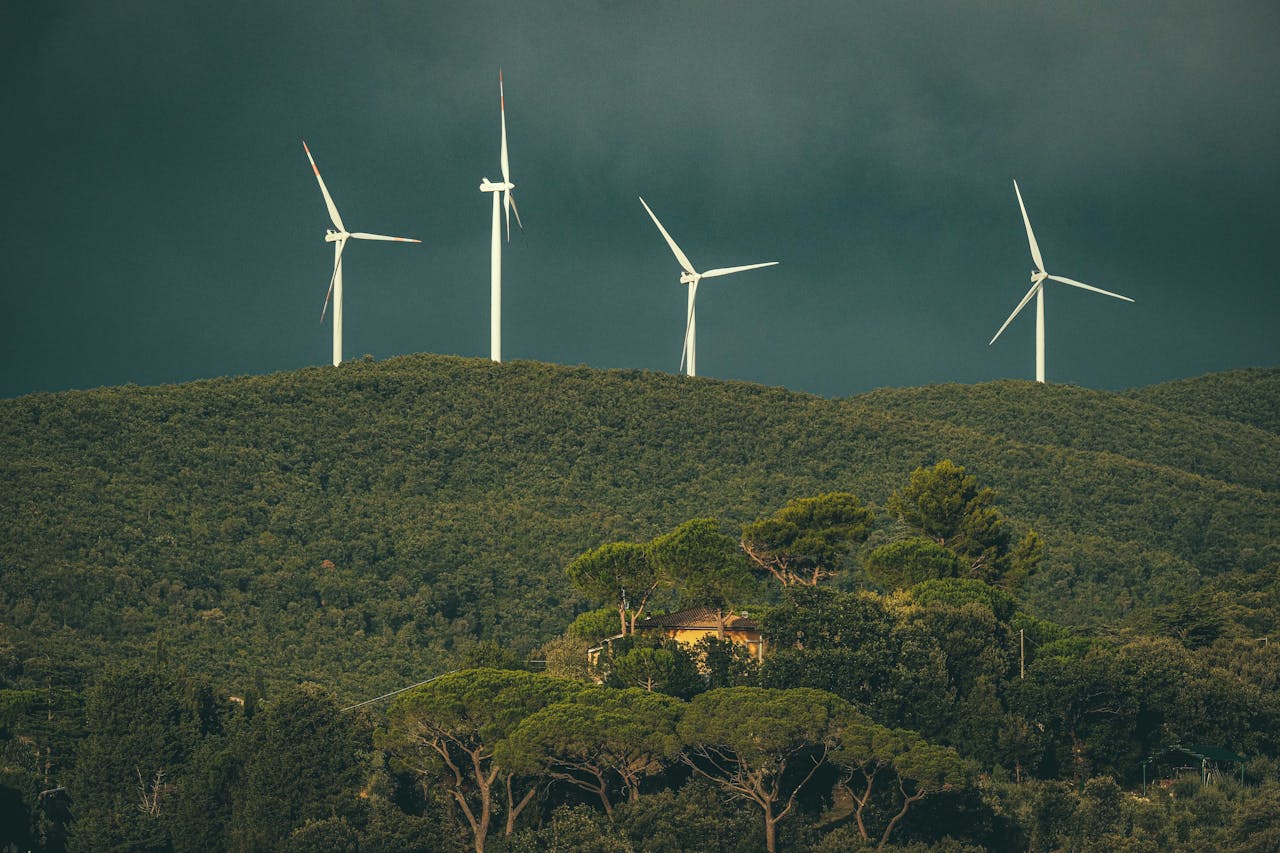 Wind turbines stand above lush green hills, showcasing renewable energy in nature.